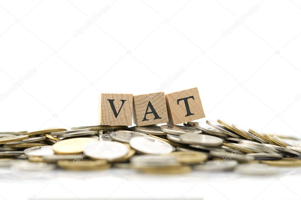 Wood word VAT is placed on a pile of coins.using as background business concept and finance concept with copy spaces for your text or design.