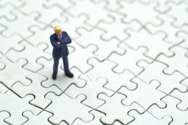 Minyatür insanlar işadamları Instalar Jigsaw beyaz. arka plan iş kavramı ve ekonomi kavramı kopya alanı ile metin veya tasarım için kullanma.