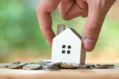 Bir modeli ev modeli tutan işadamı coins.using arka plan iş kavramı ve gayrimenkul kavramı kopya alanı metin veya tasarım ile bir yığın yerleştirilir.