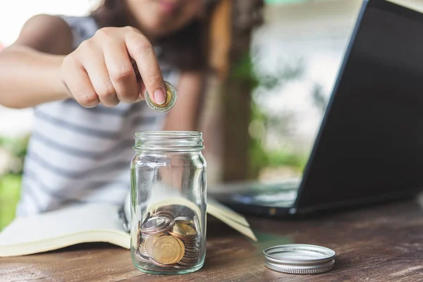 Businesswomen Put the coin in a glass jar To save money, save mo