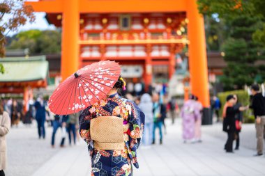 Kırmızı tahta Tori Kapısı 'nın arasında Japon kimonosu giyen geyşalar. 