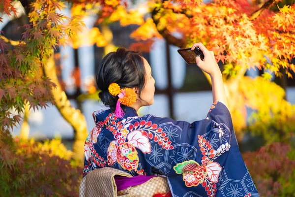 赤い木製の鳥居の中に日本の着物を着た芸者の女の子 — ストック写真
