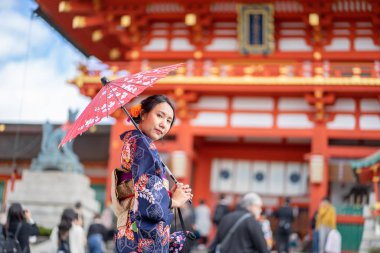 Kırmızı tahta Tori Kapısı 'nın arasında Japon kimonosu giyen geyşalar. 