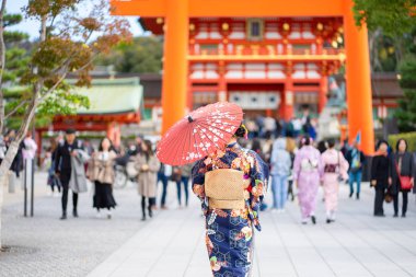 Kırmızı tahta Tori Kapısı 'nın arasında Japon kimonosu giyen geyşalar. 