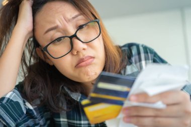 Elinde kredi kartı olan kafası karışmış genç bir kadın.