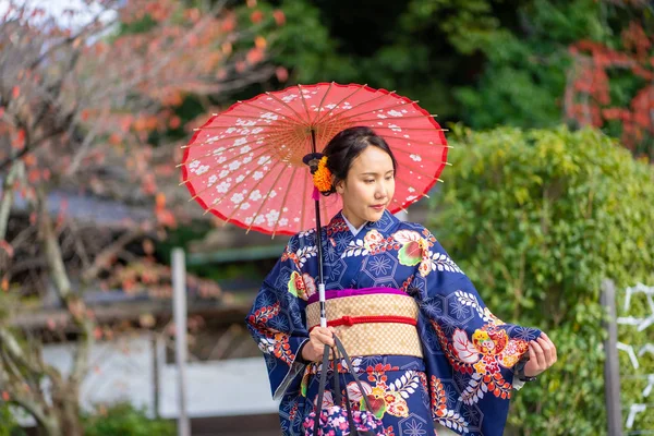 Geishas Mädchen mit japanischem Kimono zwischen rotem Tori-Tor aus Holz — Stockfoto