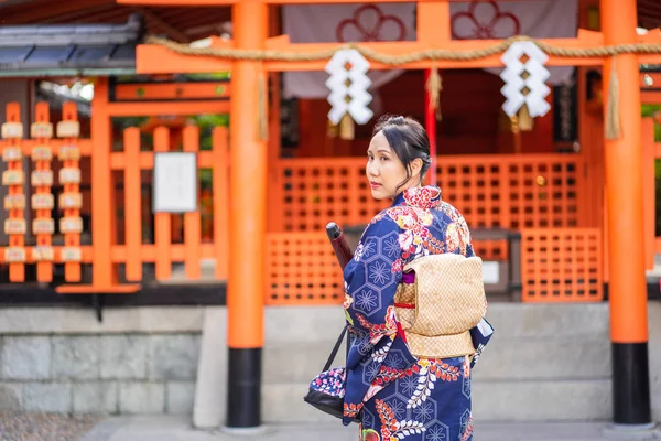 Geishas meisje draagt Japanse kimono tussen rode houten Tori Gate — Stockfoto