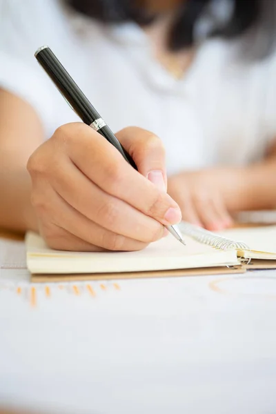 Nahaufnahme einer Geschäftsfrau, die einen Stift in der Hand hält und schreibt Stockbild