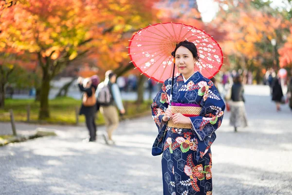 Chica geishas usando kimono japonés entre la puerta de madera roja Tori en Fushimi Inari Shrine en Kyoto, Kimono es una prenda tradicional japonesa. La palabra "kimono", que en realidad significa una "cosa para usar"" —  Fotos de Stock