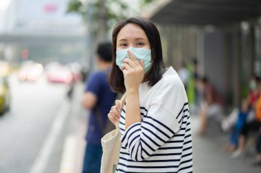 Yüz maskesi takan kadın hava kirliliğine karşı filtre koruyor (PM