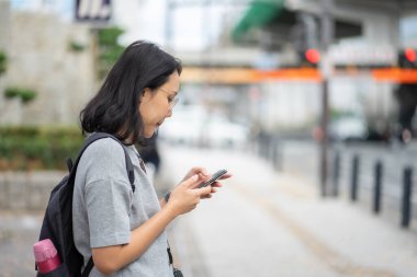 beautiful Asian woman Traveler uses a smartphone in the city cen
