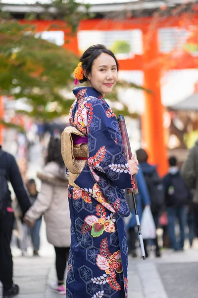 京都の伏見稲荷神社にある赤い木製の鳥居の中に日本の着物を着た芸者の女の子 着物は日本の伝統的な服です 着物という言葉は 実際には 着るもの を意味します — ストック写真