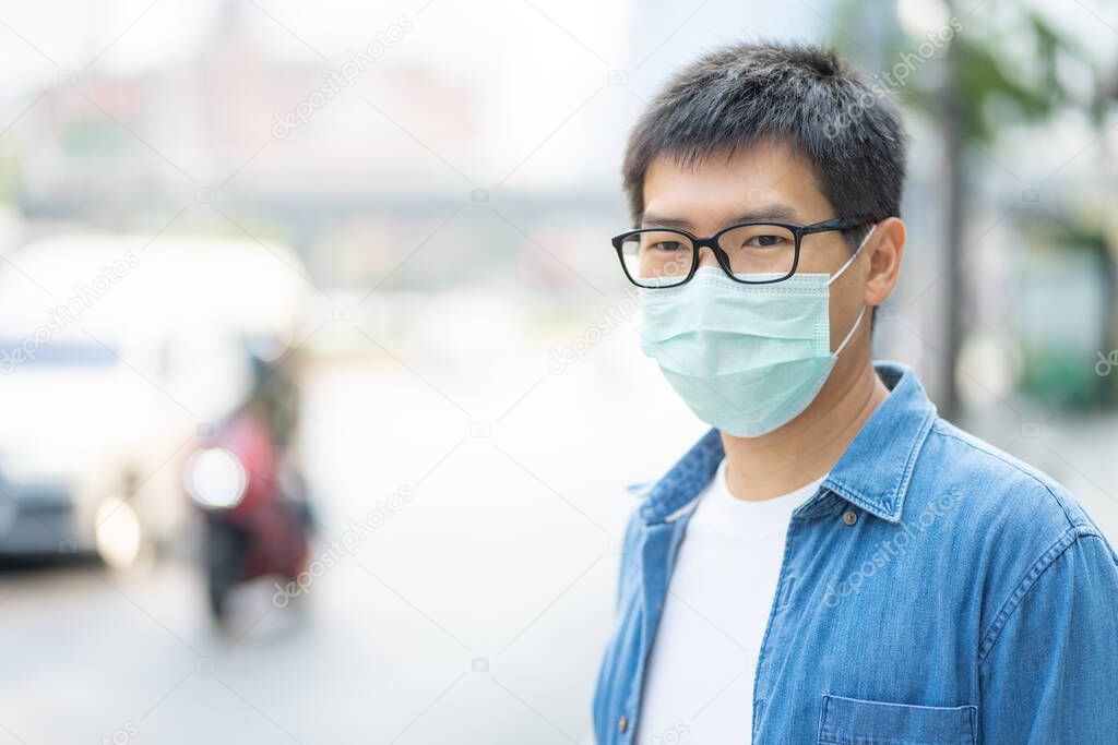 HandsomeMan wearing face mask protect filter against air pollution (PM2.5) or wear N95 mask. protect pollution, anti smog and Covid 19 viruses, Air pollution caused health problem. Global warming.