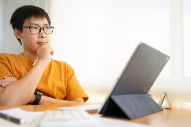 Evde çalışan genç Freelancer ya da iş adamı akıllı telefon tabletiyle çalışıyor. Çevrimiçi çalışmak ya da çalışırken öğrenmek. Ev kavramından Serbest Çalışma, İş ve Çalışma