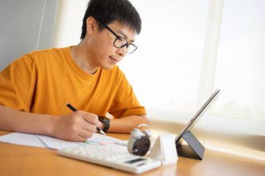 Evde çalışan genç Freelancer ya da iş adamı akıllı telefon tabletiyle çalışıyor. Çevrimiçi çalışmak ya da çalışırken öğrenmek. Ev kavramından Serbest Çalışma, İş ve Çalışma