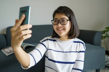 Akıllı telefonu olan, sosyal medyada gülümseyen, mesajlaşan, arkadaşlarıyla konuşan, müzik dinleyen, film izleyen güzel bir kadın. Sağlık konsepti ve mesafeyi koru