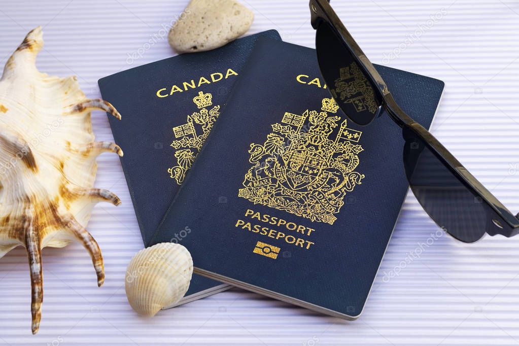 Canadian passports with sunglasses and seashells on white cardbo