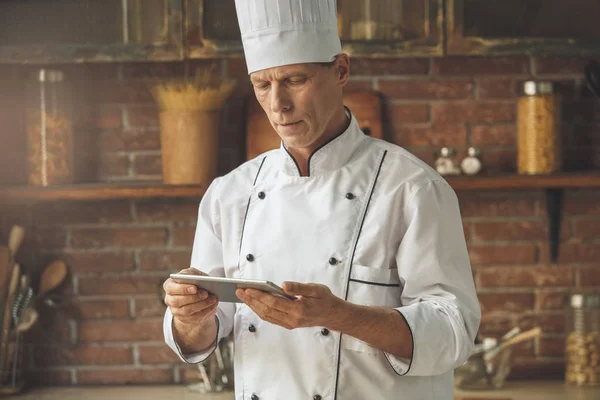 Mature man professional chef cooking meal indoors