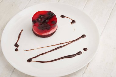 üzümü üzerinde beyaz bir plaka üzerinde bir bisküvi ile jöleli pasta