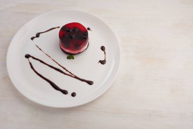 üzümü üzerinde beyaz bir plaka üzerinde bir bisküvi ile jöleli pasta