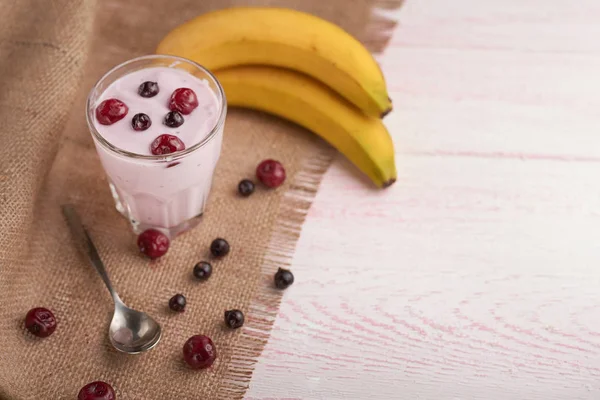 yogurt in a glass with berries on sacking and texture