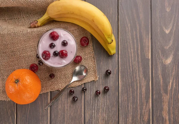 yogurt in a glass with berries on sacking and texture