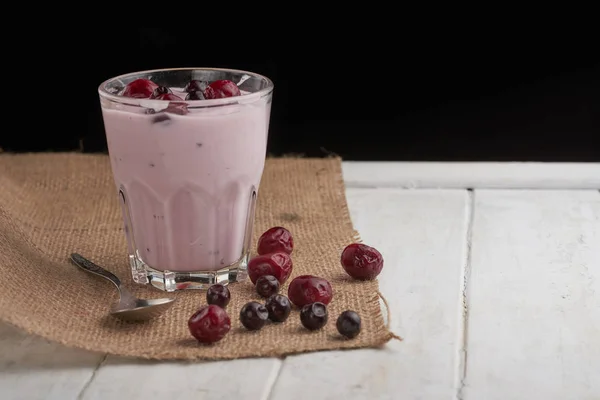 yogurt in a glass with berries on sacking and texture