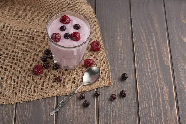 yogurt in a glass with berries on sacking and texture