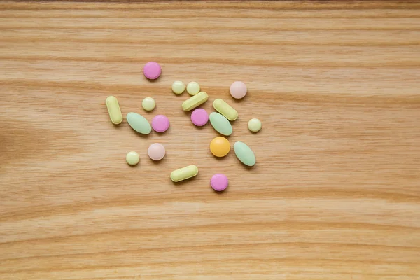 Lot of colorful pills on a wooden table — Stock Photo, Image