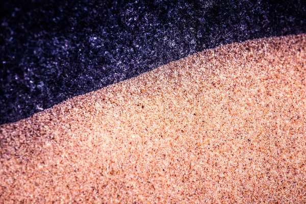 Abstraktní, vysoce kontrastní pozadí moře písku a skalní tvary. Malou hloubkou ostrosti, fialový barevný tón. — Stock fotografie