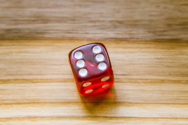 Een doorschijnend rood zes zijdige spelen dobbelstenen op een houten achtergrond — Stockfoto