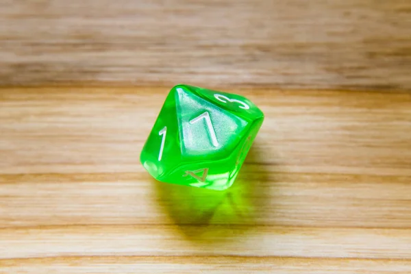 Průsvitný Zelený deset oboustranný hrací kostky na dřevěné poza — Stock fotografie