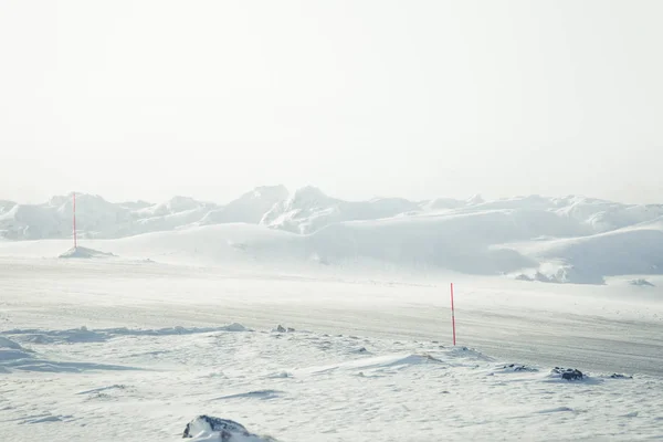 Un bellissimo paesaggio con una strada bianca e innevata con pali di sicurezza in inverno norvegese — Foto Stock