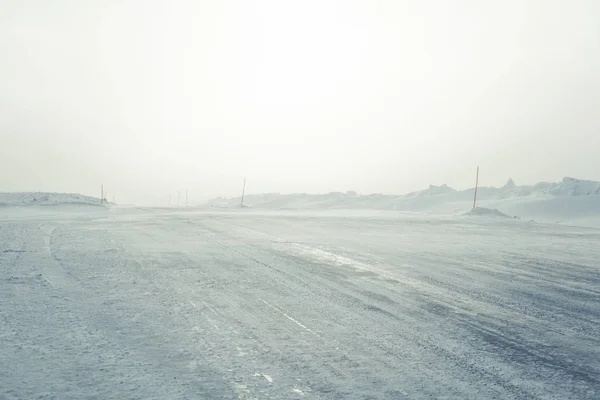 Uma bela paisagem com uma estrada branca e nevada com postes de segurança no inverno norueguês — Fotografia de Stock
