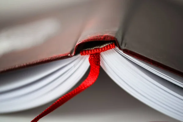 Un bellissimo primo piano di un libro in copertina rosso scuro e con segnalibro rosso. Profondità di campo ridotta — Foto Stock