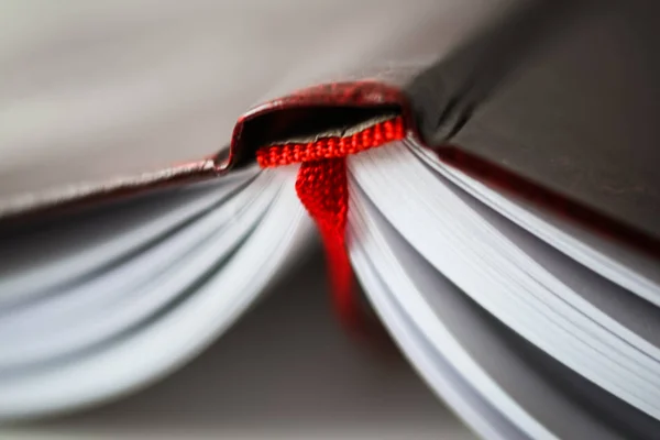 Een mooie close-up van een boek in donker rode kaft en met rode bladwijzer. Ondiepe scherptediepte — Stockfoto