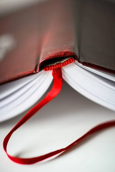 Eine schöne Nahaufnahme eines Buches in dunkelrotem Einband und mit rotem Lesezeichen. geringe Schärfentiefe — Stockfoto