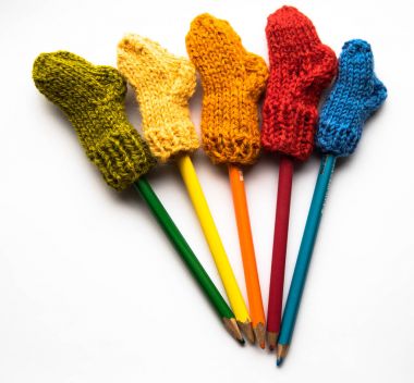 Küçük, örme Yün çorap ışık arka plan üzerinde renkli kalemler ile el