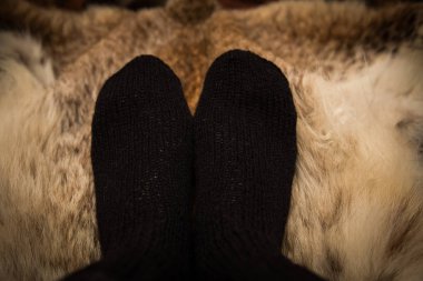 Sıcak el bir kürk zemin üzerine yün çorap ördü. İlk kişi görünümü.