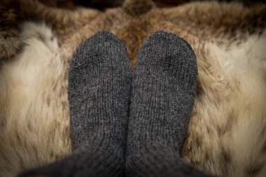 Sıcak el bir kürk zemin üzerine yün çorap ördü. İlk kişi görünümü.