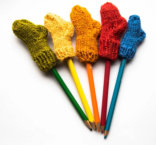 Küçük, örme Yün çorap ışık arka plan üzerinde renkli kalemler ile el