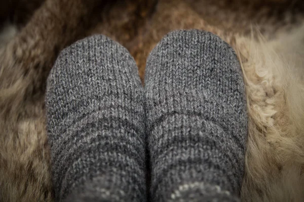 Sıcak el bir kürk zemin üzerine yün çorap ördü. İlk kişi görünümü.