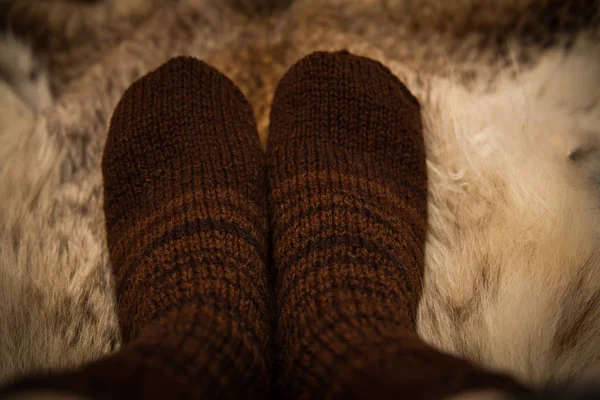 Sıcak el bir kürk zemin üzerine yün çorap ördü. İlk kişi görünümü.