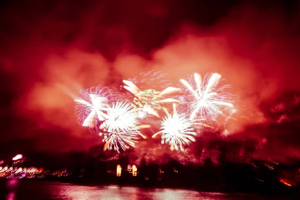 Photo colorée abstraite, floue et de style bokeh de feux d'artifice dans un ton rouge au-dessus de la rivière — Photo