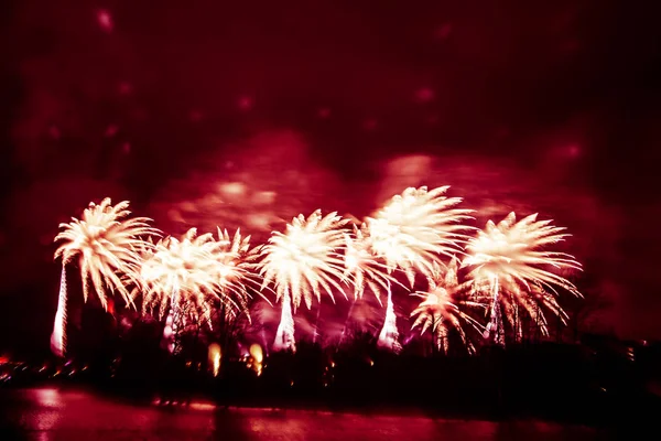 Abstraktes, verschwommenes, im Bokeh-Stil farbenfrohes Foto von Feuerwerk in einem Rotton über dem Fluss — Stockfoto