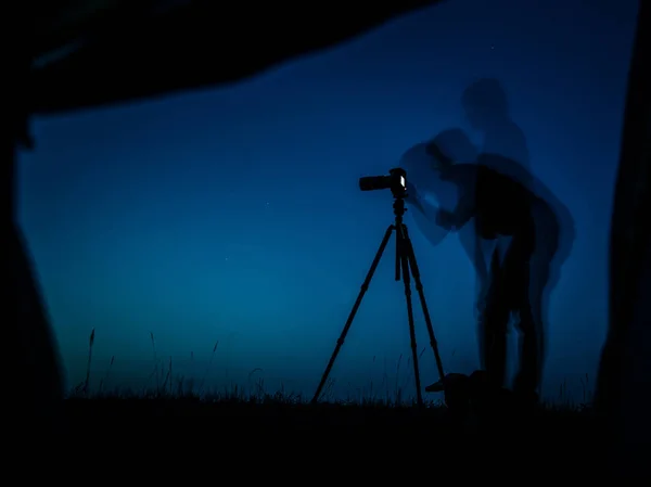 Artistic long exposure photo of a photographer in action. Multiple silhouettes and a camera un tripod.  A view from a tent in night — Stock Photo, Image