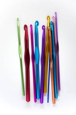 Beyaz bir arka plan üzerinde renkli tığ işi iğne. Bir sürü el zanaat aletleri.