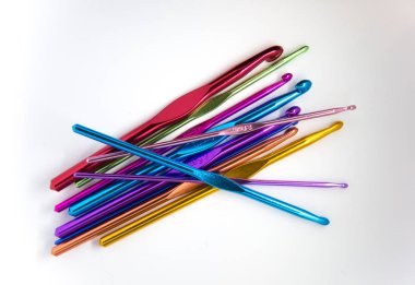 Beyaz bir arka plan üzerinde renkli tığ işi iğne. Bir sürü el zanaat aletleri.