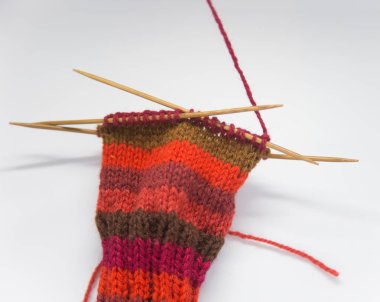 Bir kadın kırmızı yün örgü çorap. Yakın beyaz bir arka plan üzerinde örgü. El sanatları. Örgü beceri ayrıntılı Görünüm.