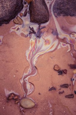 Renkli desenler sahil kumu petrol. Kirliliği desenleri Baltık Denizi kıyısında. Ekolojik bir konuda renkli, soyut şekiller.